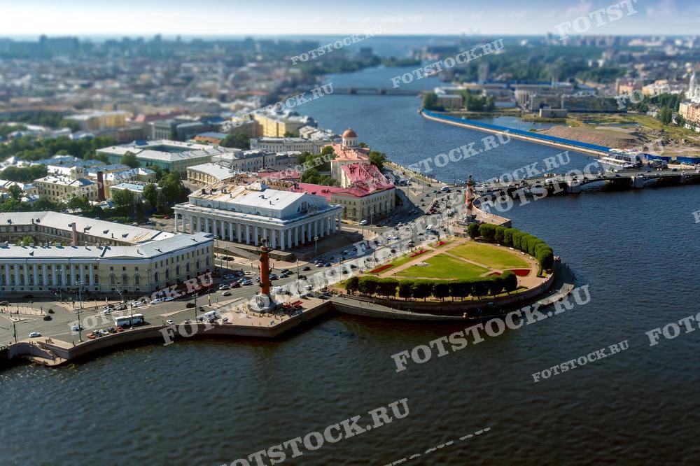Hа фотографии изображена Стрелка Васильевского острова в Санкт-Петербурге. Это одно из наиболее узнаваемых мест города, где находятся Ростральные колонны и здание Биржи. Фотография сделана с высоты, что позволяет увидеть расположение исторических объектов относительно водных пространств города. Изображение может быть использовано в туристических буклетах, образовательных материалах, научных работах, а также как украшение статей о Санкт-Петербурге или как часть визуального контента в путеводителях.